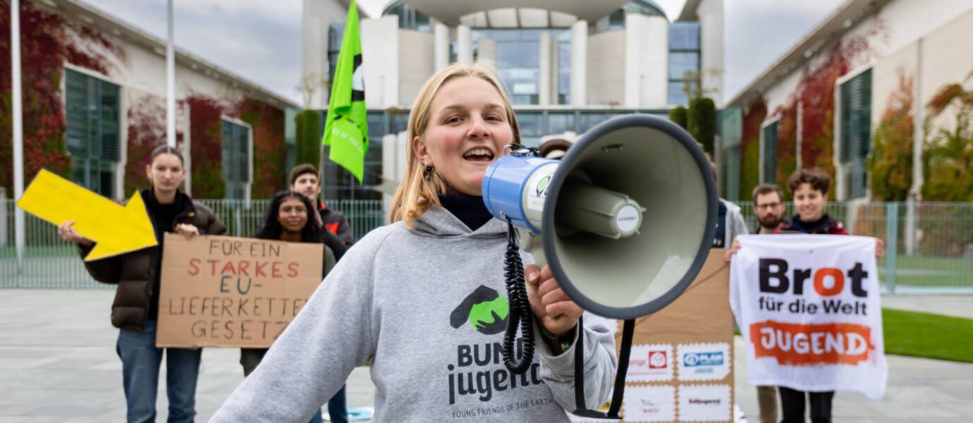 Demonstrierende mit Megafon vor Regierungsgebäude