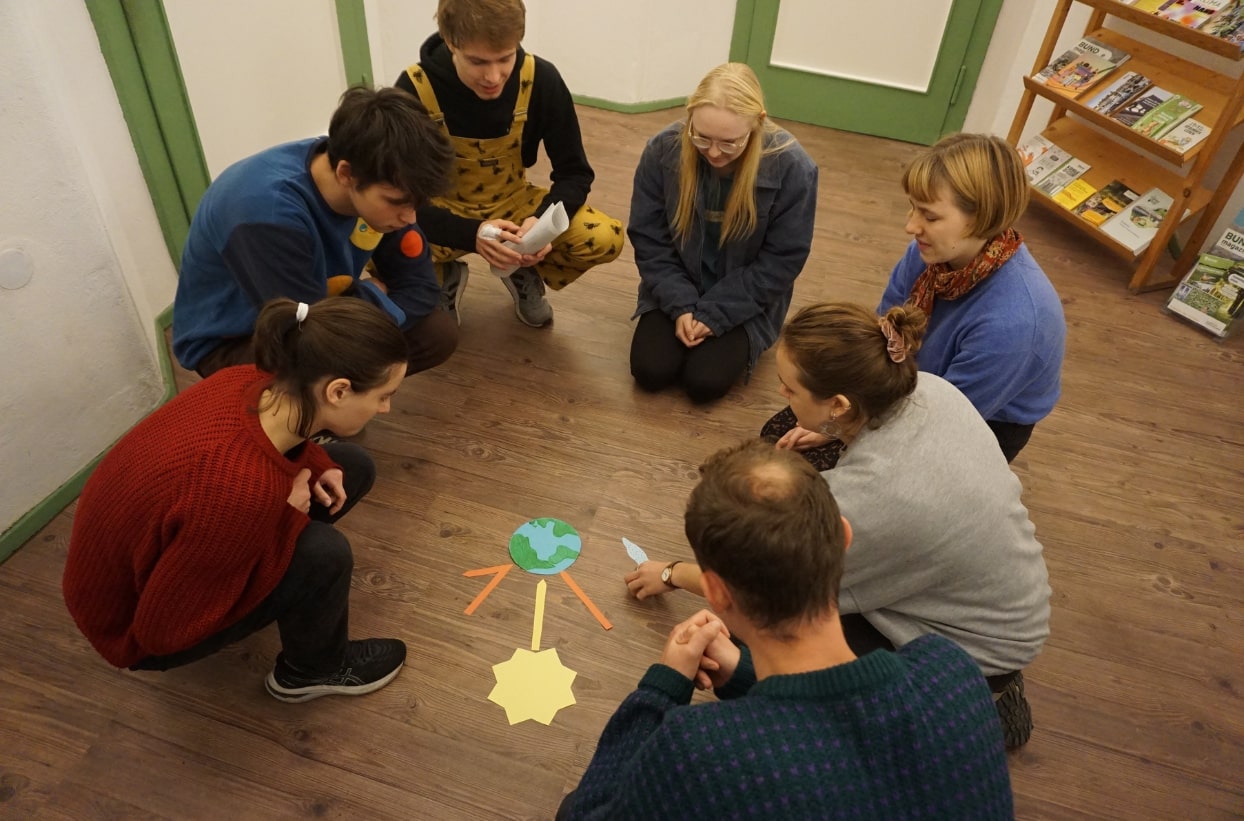 Personen diskutieren über ein Bodenmodell der Erde.
