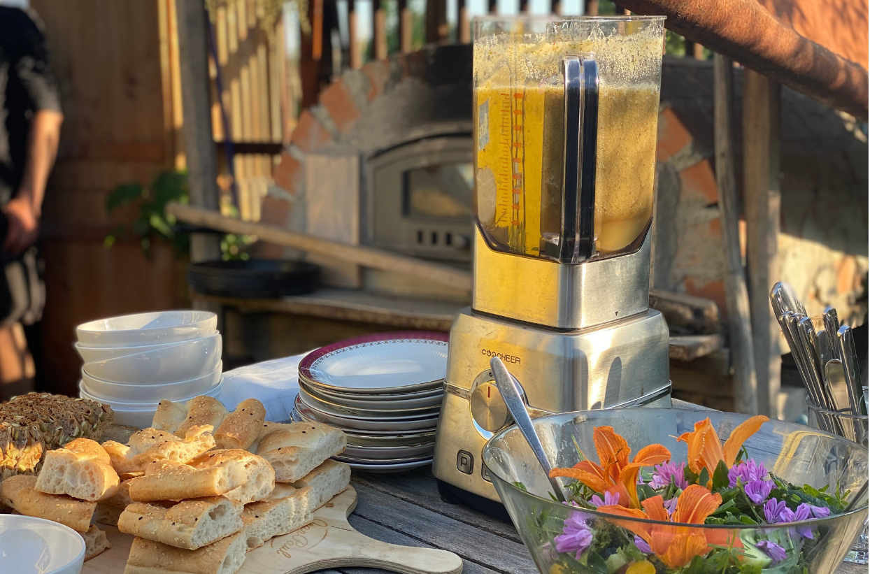 Tisch mit Mixgerät, Brot, Salat und Geschirr