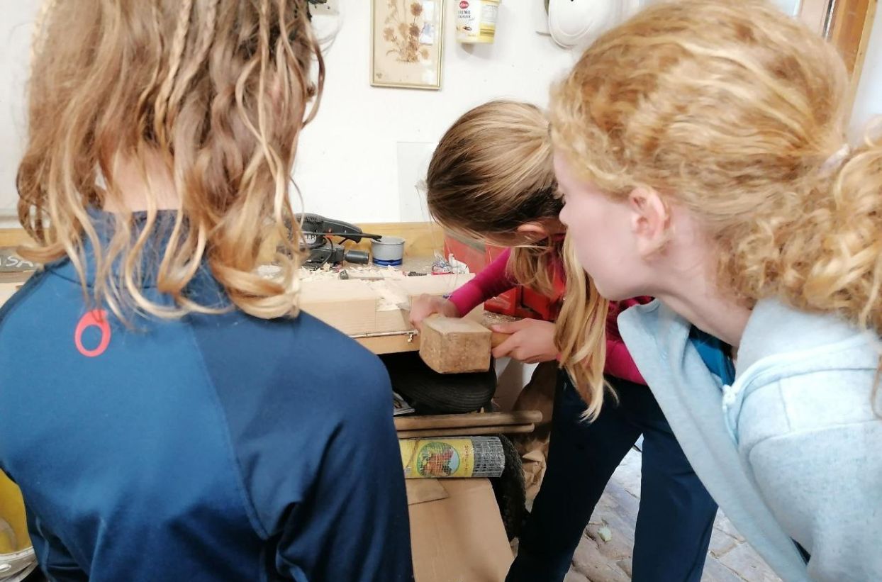 Kinder arbeiten gemeinsam an Holzprojekt.
