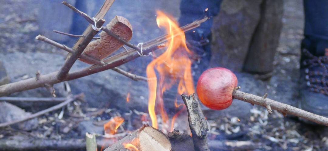 Apfel und Brot am Stock über Lagerfeuer