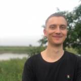 Junger Mann lächelt vor Naturhintergrund